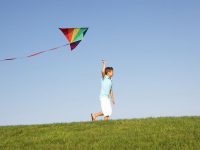 Young Boy Runs With Kite Through Field