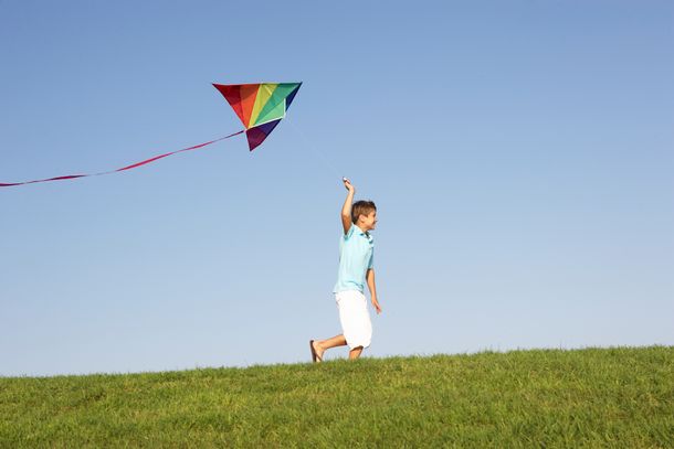 Young Boy Runs With Kite Through Field