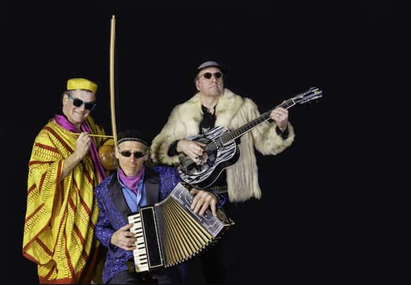 The three members of the band Craicdown, playing a guitar, accordion and a gourd 