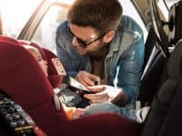 Father Fasten His Little Baby In The Car Seat