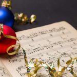 Red christmas ball with gold ribbon, on sheet music