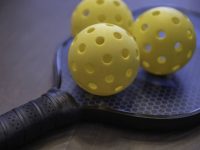 three pickleballs on a pickleball paddle