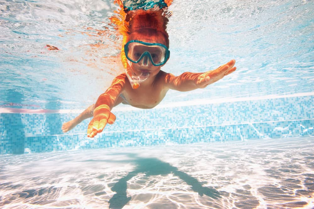 child swimming under water with mask