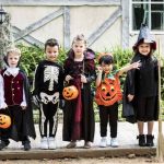children in Halloween costumes standing on the sidewalk