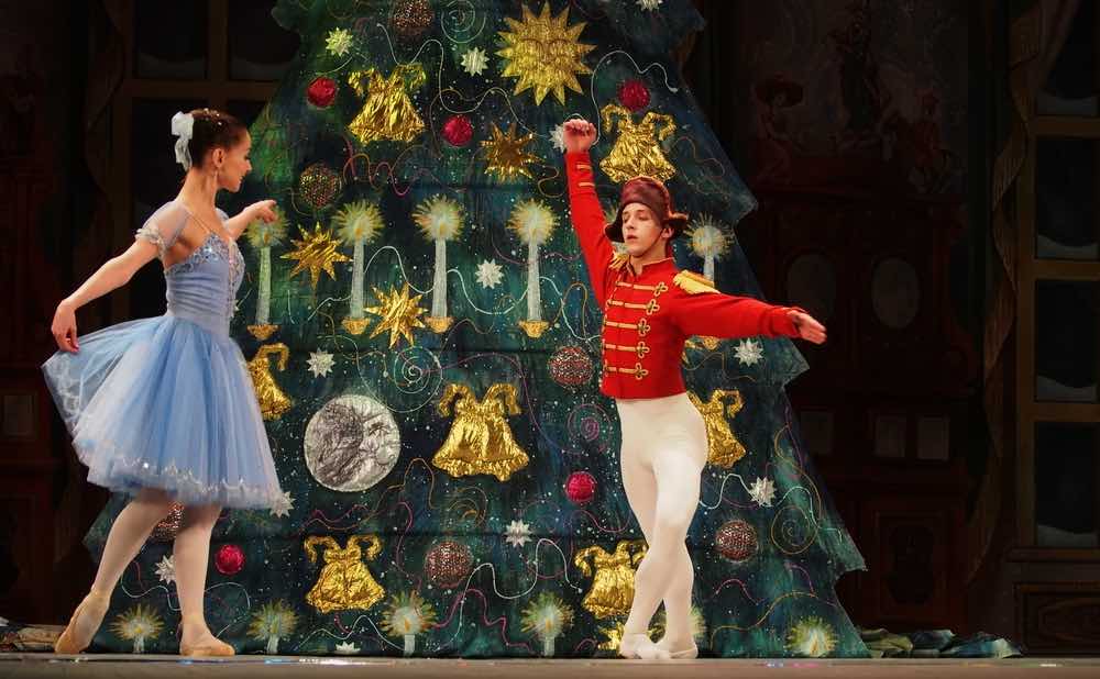 Two dancers in front of a Christmas tree during a production of The Nutcracker