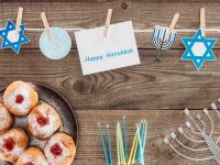 Hanukkah symbols on flat surface: menorah, candles, jelly donuts