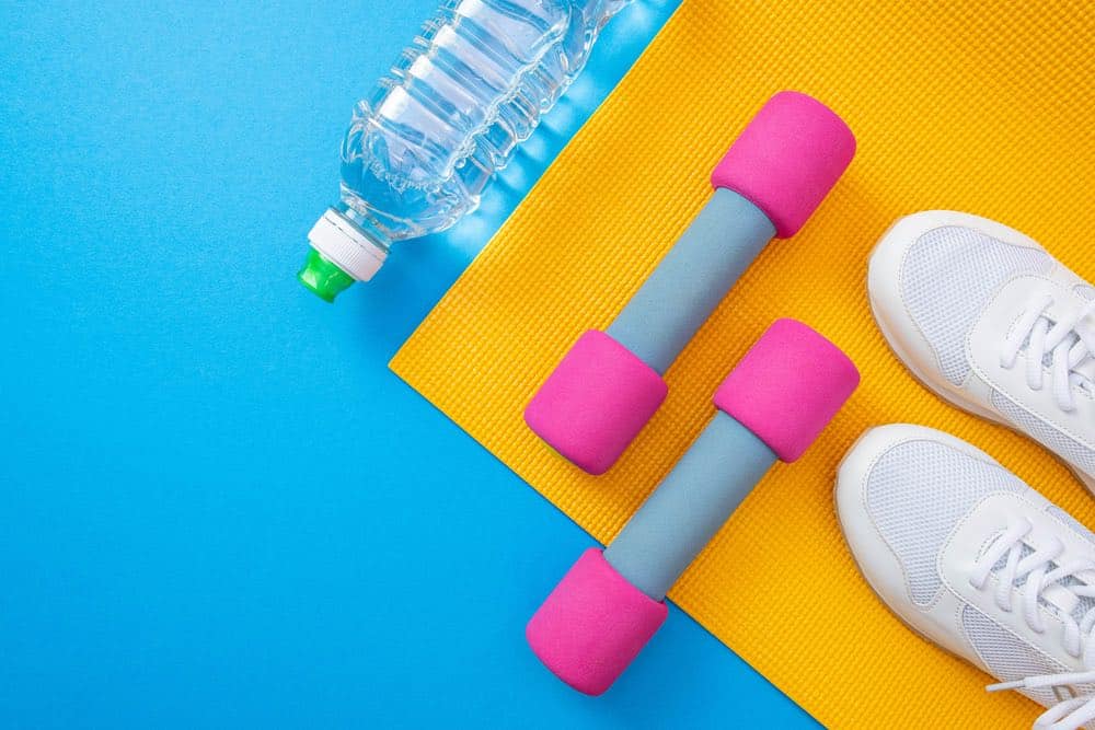 hand weights, athletic shoes and a water bottle on an exercise mat