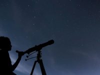 person looking through a telescope at night