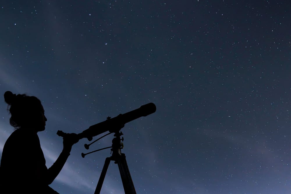 person looking through a telescope at night