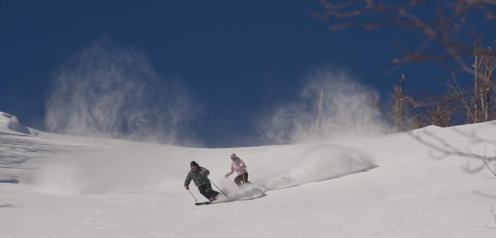 Two people skiing down Sugar Mountain