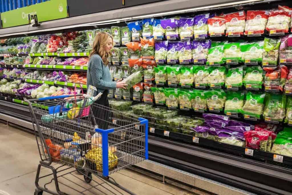 woman shopping in produce aisle, looking at lettuce