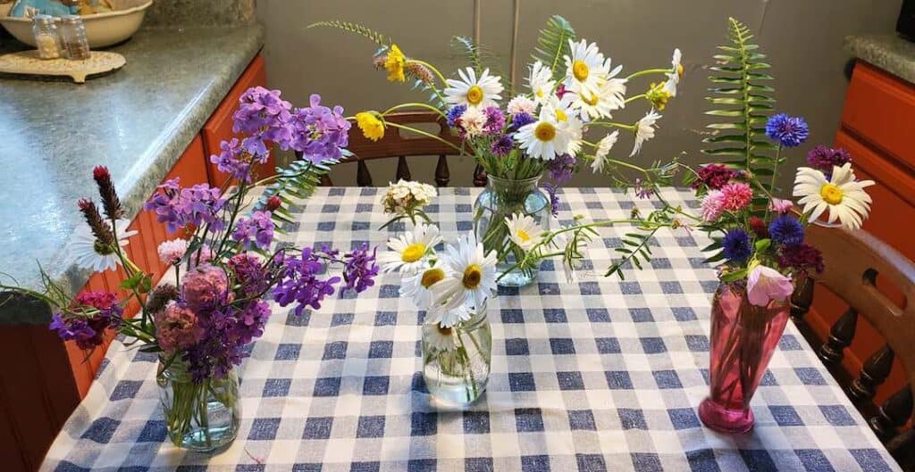 Five bouquets of flowers on a blue and white checked table cloth