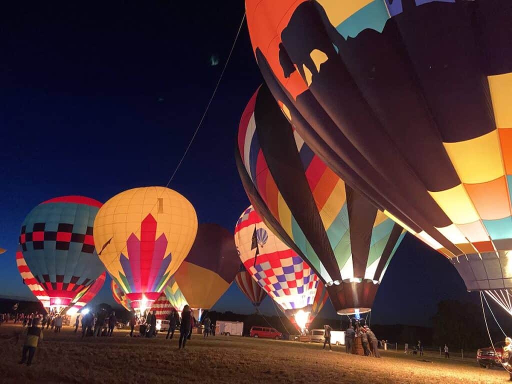 several hot air balloons glowing at night