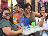 women playing connect 4 at a table outside. Adult Recess in Raleigh