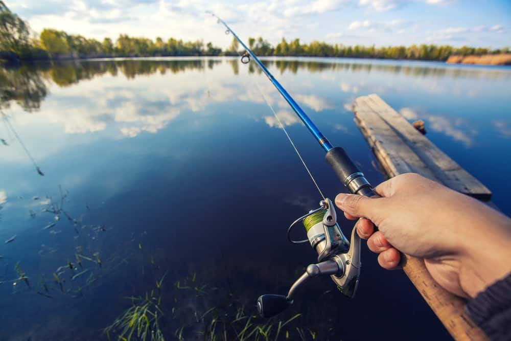 closeup of a hand holding a fishing rod, fishing in lake