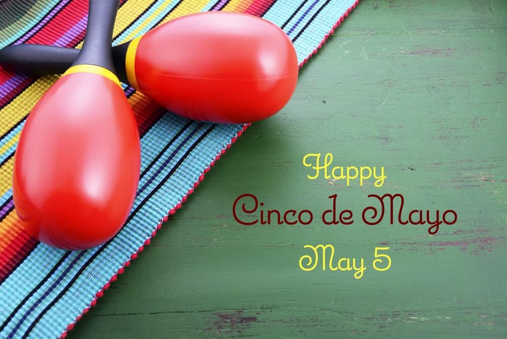 Happy Cinco de Mayo background with colorful maracas on Mexican theme dark green distressed table 