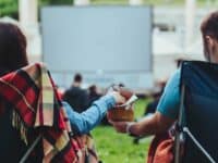 Couple sharing popcorn while watching an outdoor movie