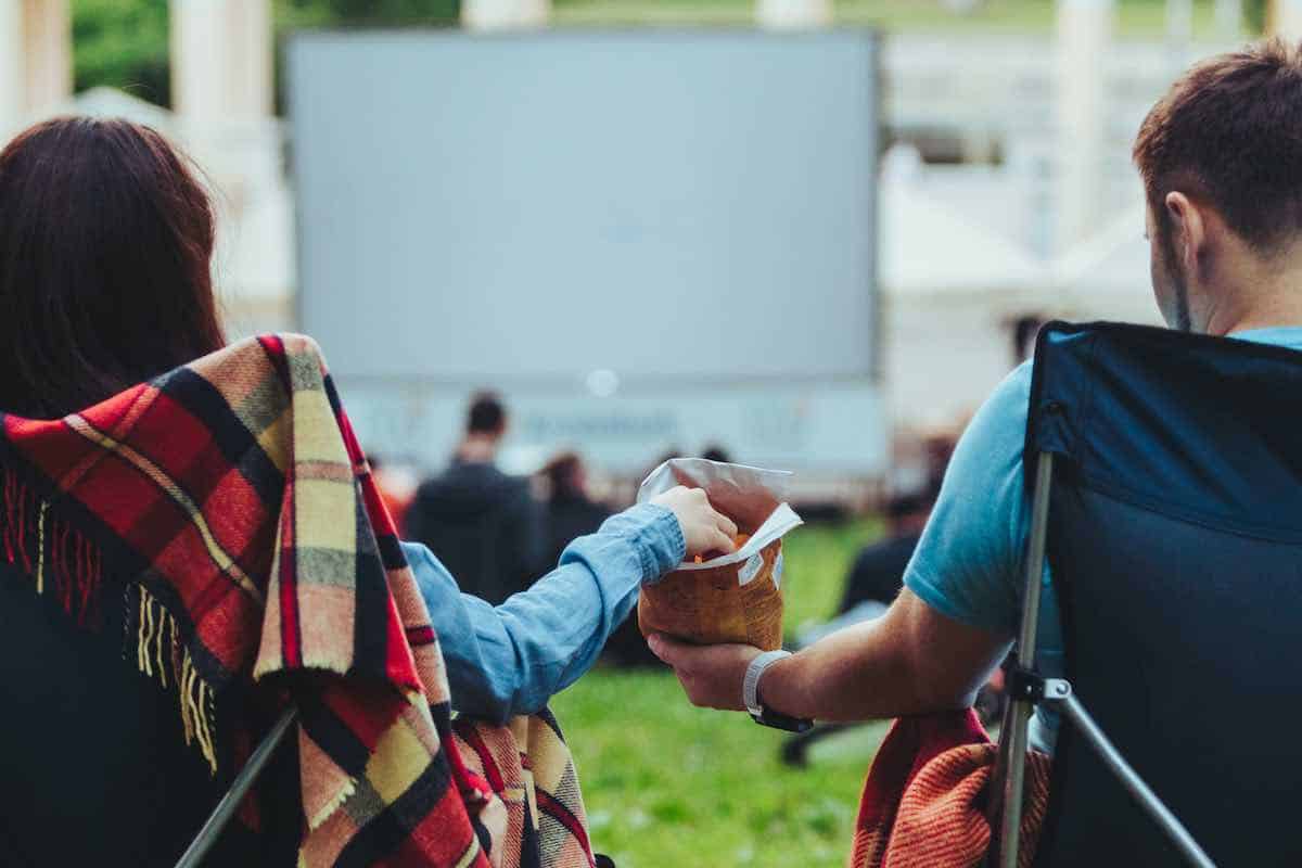 Couple sharing popcorn while watching an outdoor movie