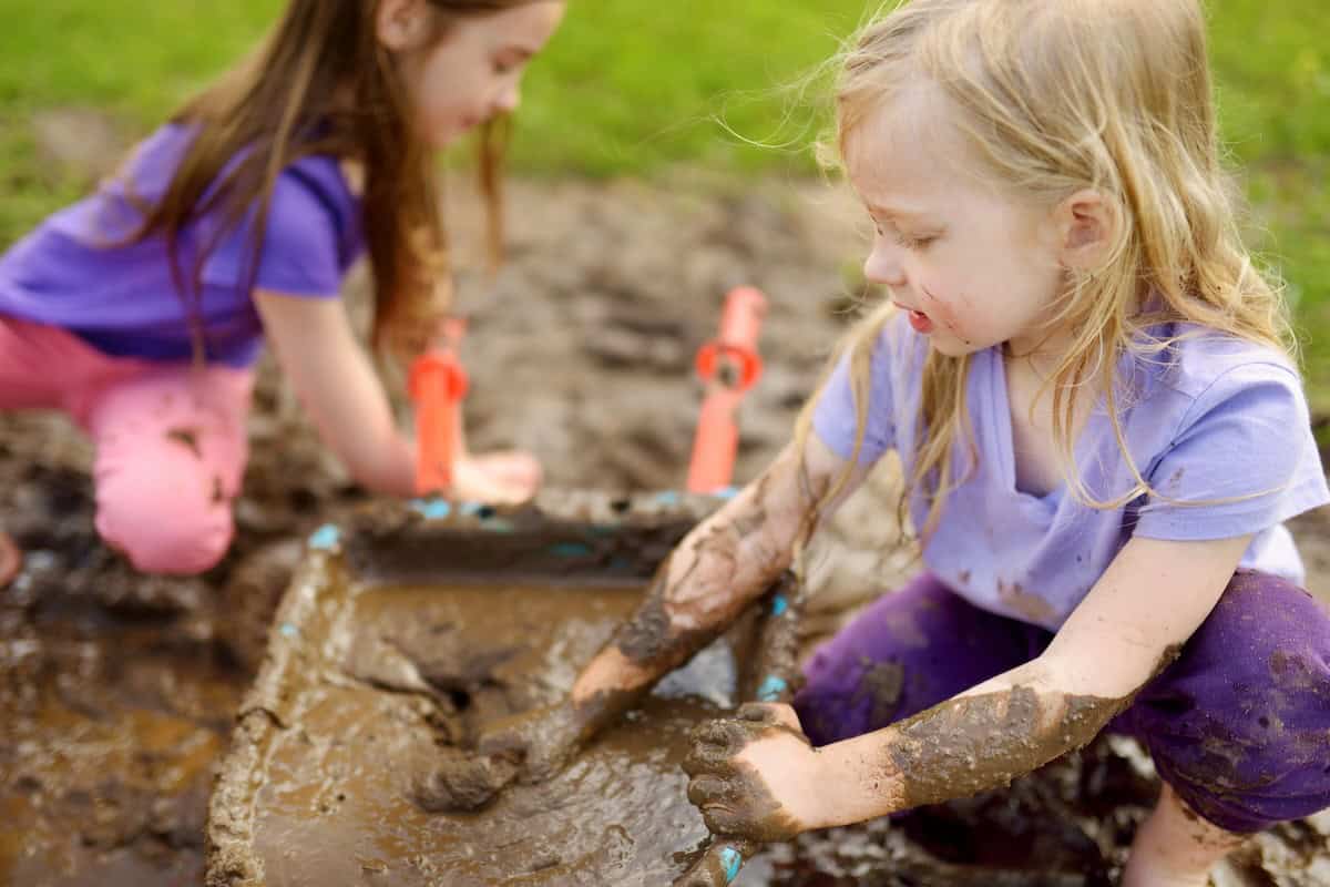 two girls playing in mud
