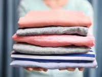 Woman holding pile of clean folded clothing