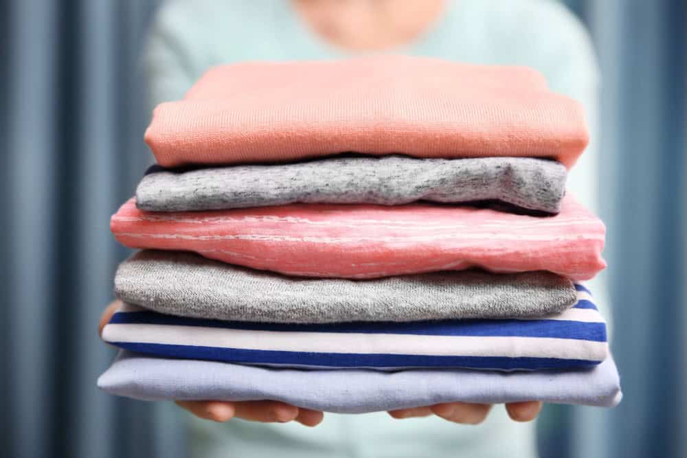 Woman holding pile of clean folded clothing
