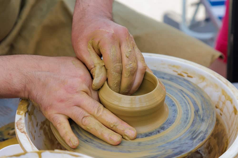 potter working with clay on pottery wheel