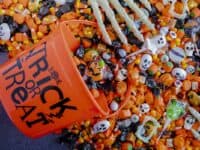 trick or treat bucket with candy spilling out and a skeleton hand