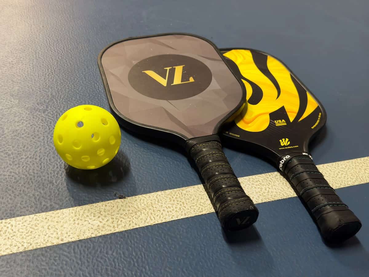 Two pickleball paddles and ball on court