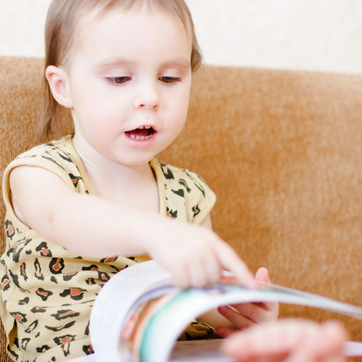 Toddler sitting on couch reading book