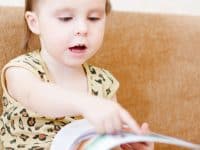 Toddler sitting on couch reading book
