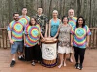 people in tie dye shirts and a drum